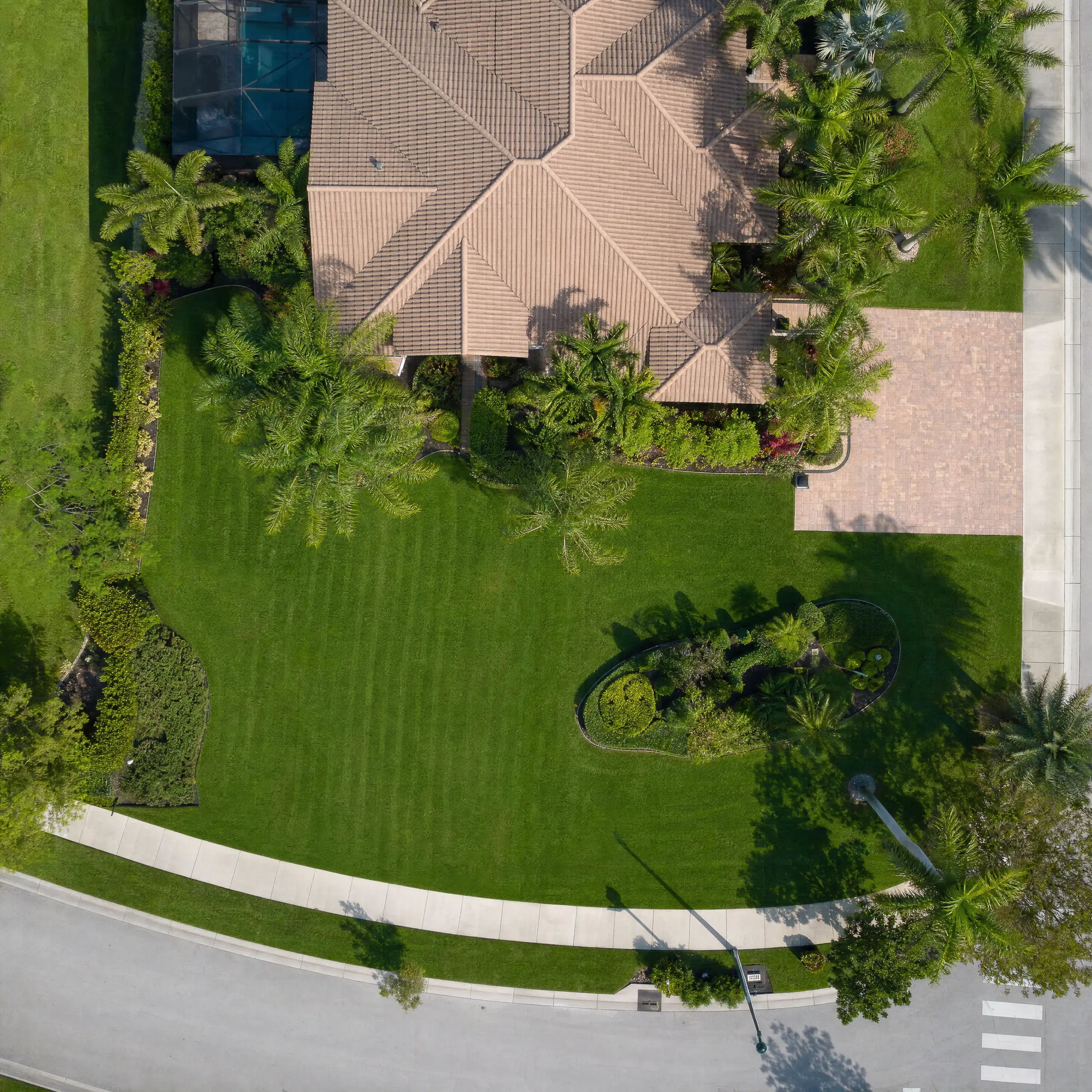 An aerial of a Florida property with pool, tile roof, and green lawn