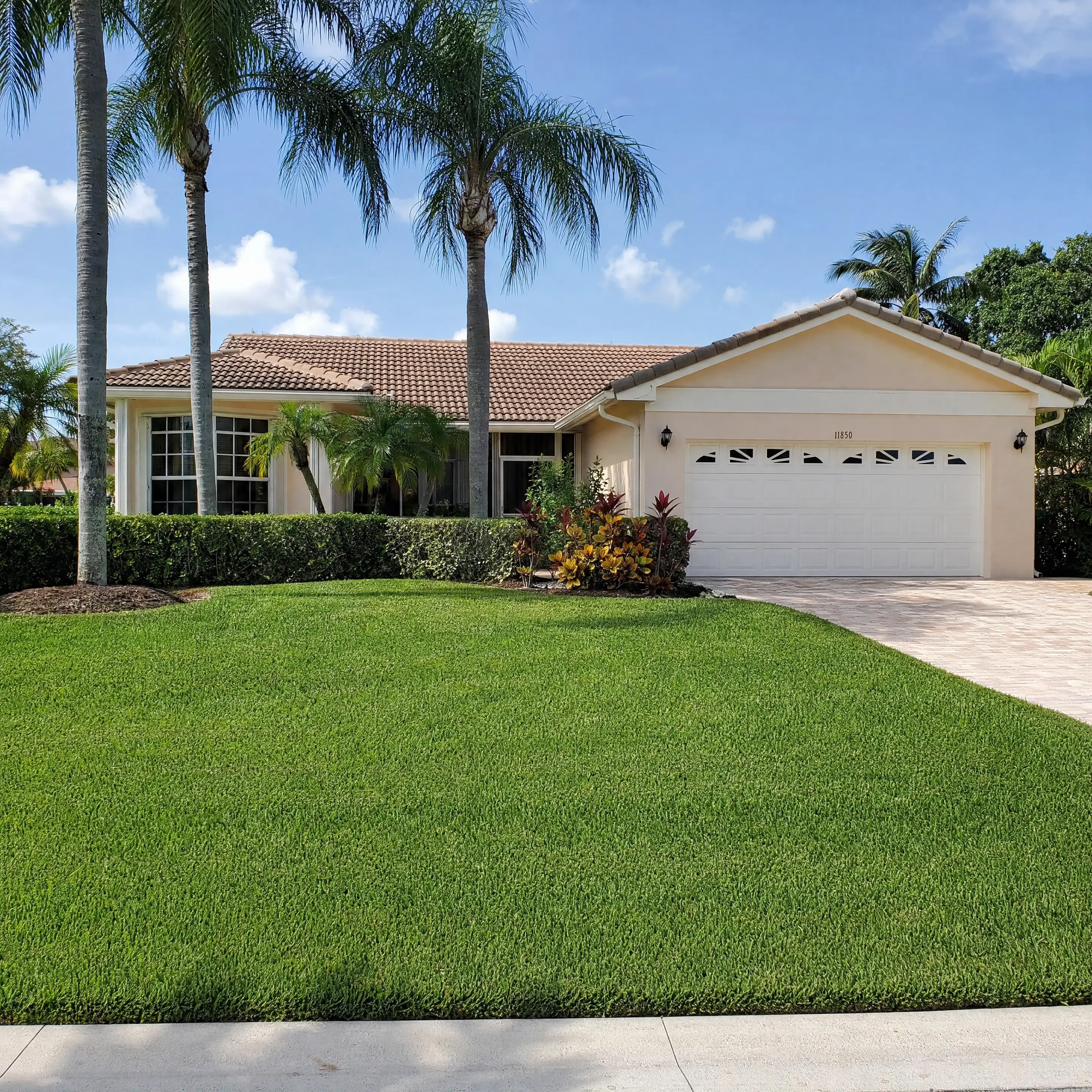 A beige Florida home with a wide front lawn in Port St. Lucie