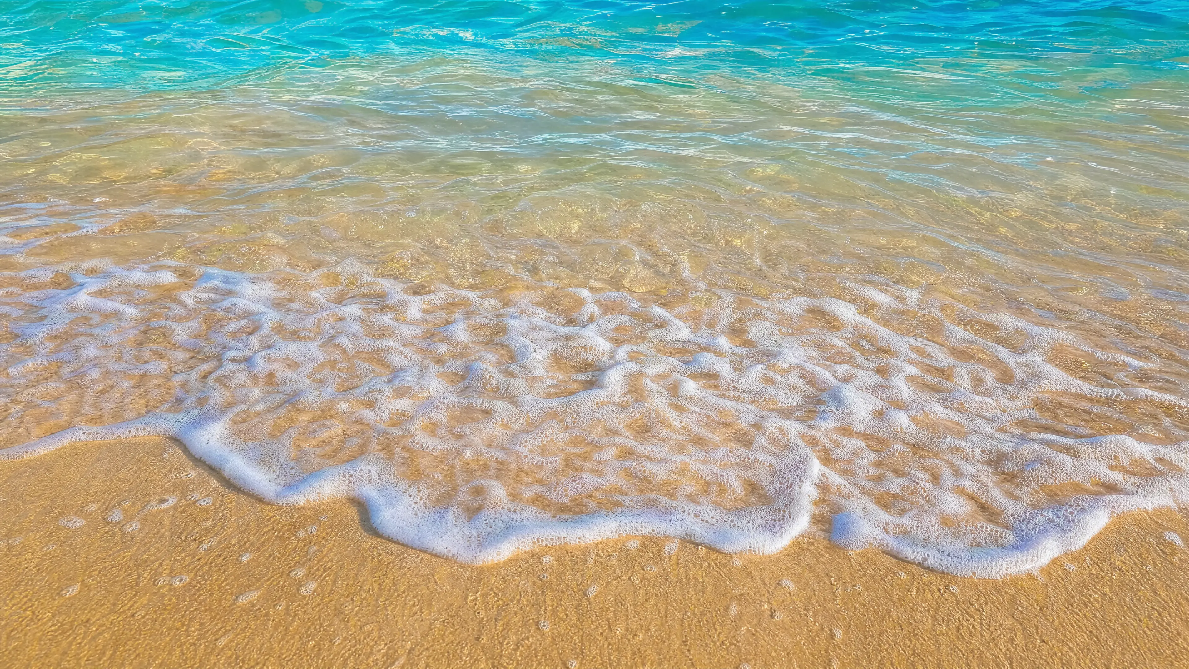 Turquoise water washing over a beige Florida sand beach