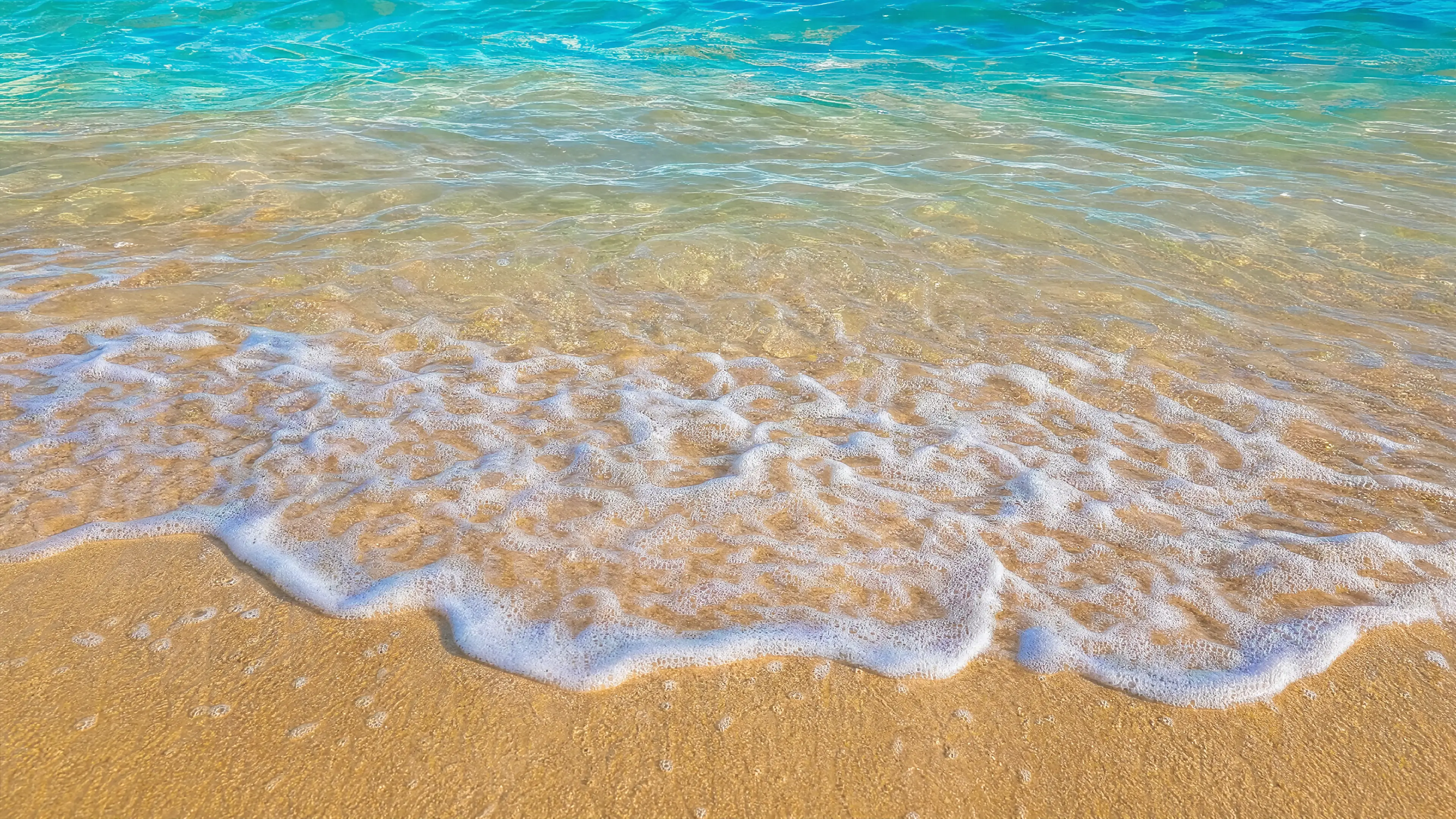 Turquoise water washing over a beige Florida sand beach